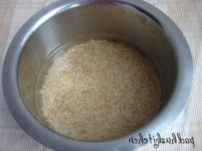 Hvordan koke ris i en riskoker. Mål ris med en kopp og legger den i en gryte.