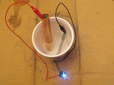 Hvordan å lage en hjemmelaget batteri. Helle innholdet i en soda kan i en plastkopp.